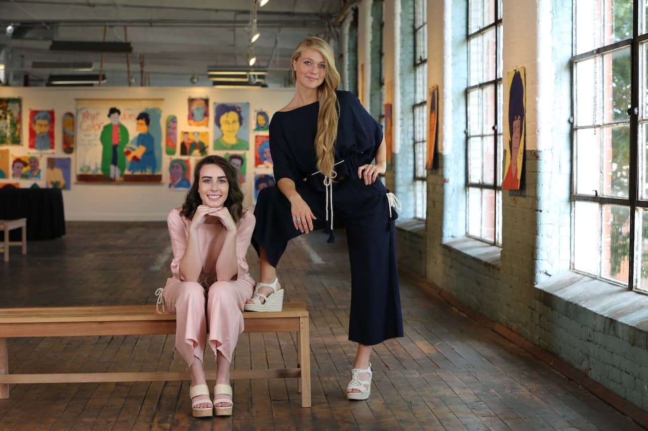 Two women wearing jumpsuits in an art studio